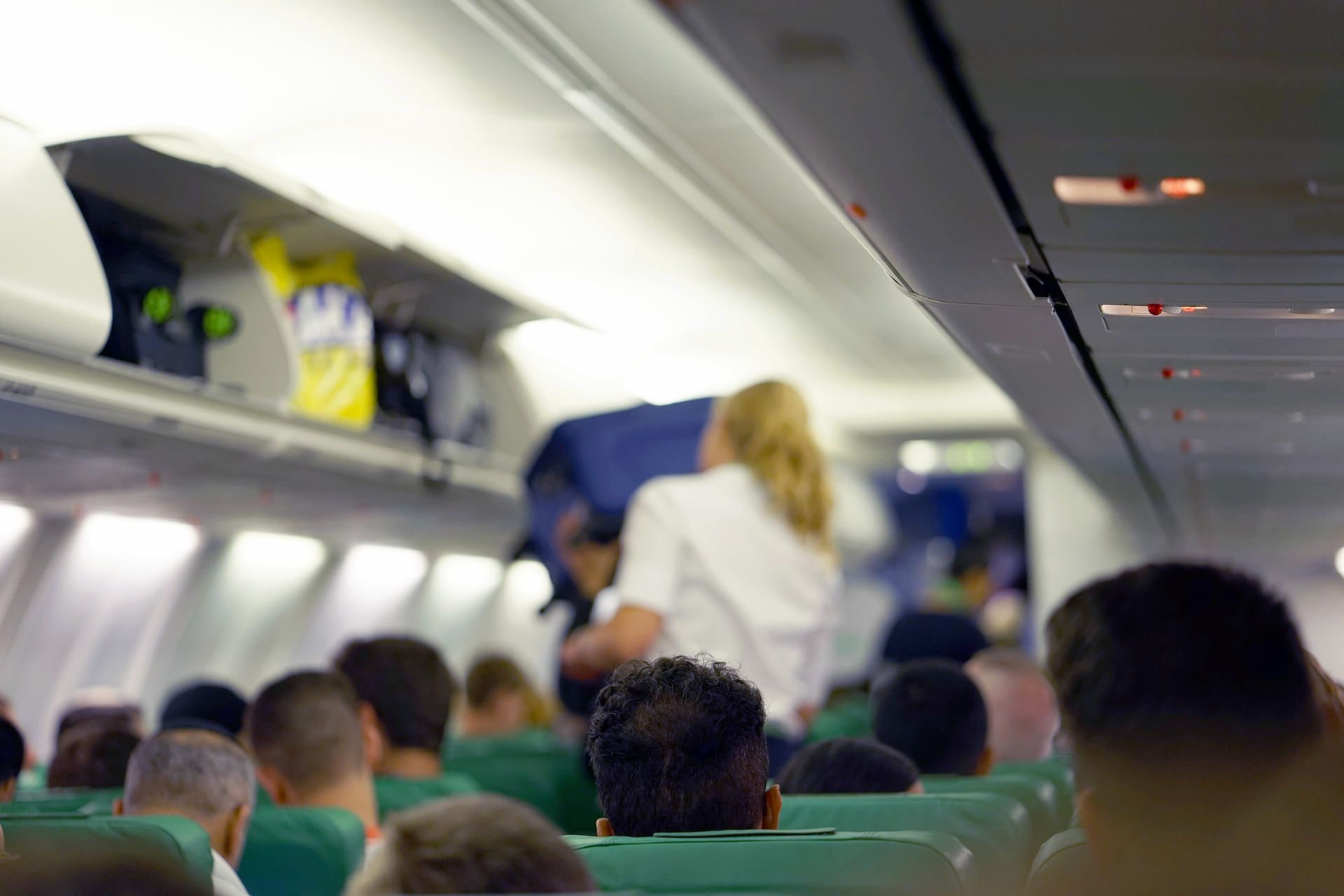 stewardess helping seated passengers to load their luggage